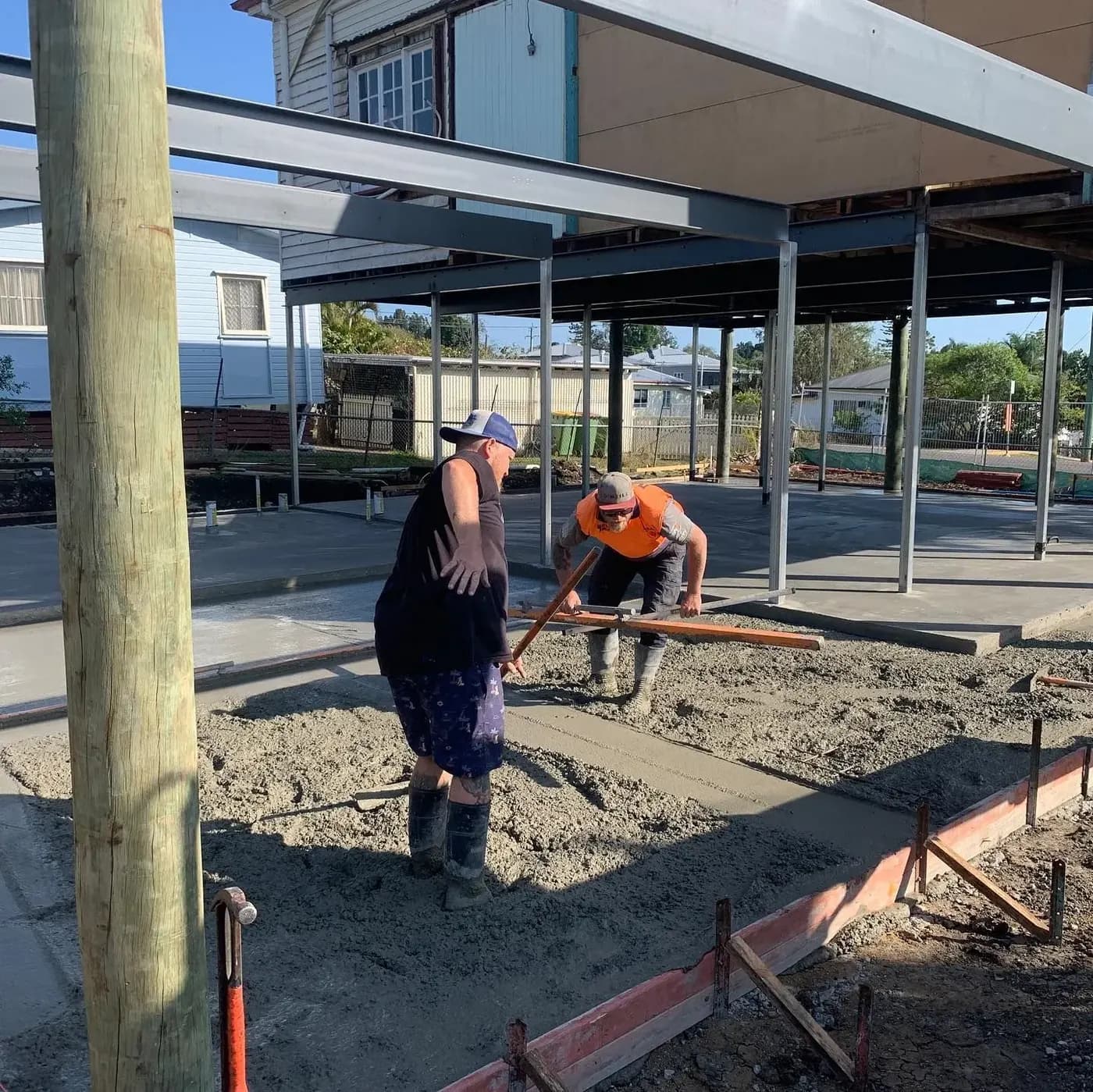 Tradesman setting a new stump footing beneath a house